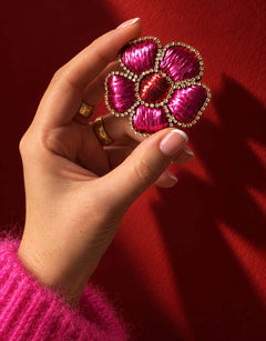 Broche fleur fuchsia et rouge tenue en main.