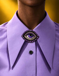 Broche Œil Céleste violette épinglée au col d’une chemise lilas