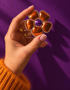 Broche fleur orange et violette tenue en main.