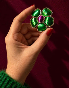 Broche fleur verte et violette tenue en main.